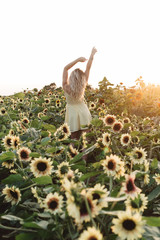 A women in her twenties with blonde hair exploring a sunflower field at sunset