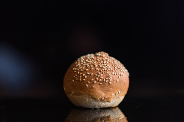 Bun with sesame seeds on a black background.