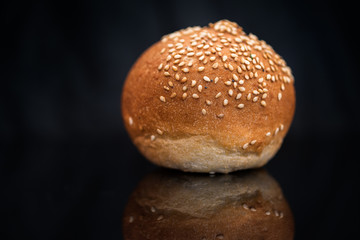 Bun with sesame seeds on a black background.
