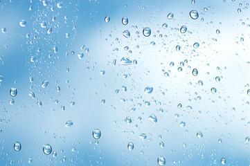 Fototapeta na wymiar Water drops of rain on blue glass background