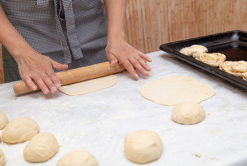 Girl rolls the dough in the kitchen