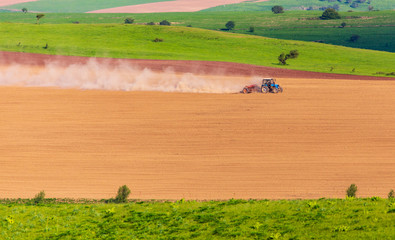 Dust from a tractor working in a field in spring