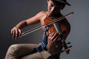 In selective focus of human hand pressing string of violin,show how to play the acoustic instrument,blurry light around