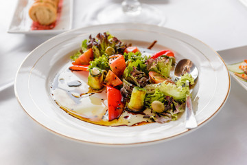 Served table at the banquet. Salad of zucchini and tomatoes with olives and black sesame