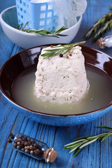Homemade cheese in the brine on the blue wooden table