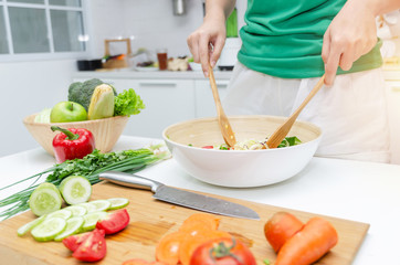 Diet. young pretty woman in green shirt standing and preparing the vegetables salad in bowl for good healthy in modern kitchen at home, healthy lifestyle, cooking, healthy food and dieting concept