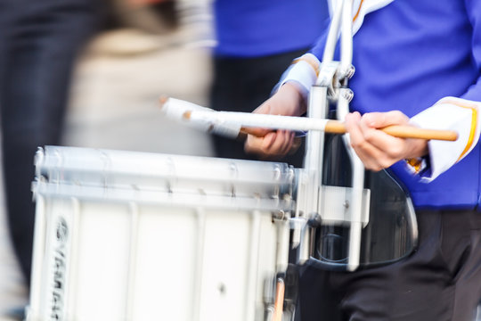 Motion blur snare drummer in blue and white uniform  playing drum in a march.
