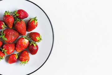 Fresh ripe strawberries in a plate on a natural white stone background. Copy space. The idea of a healthy Breakfast. Close-up