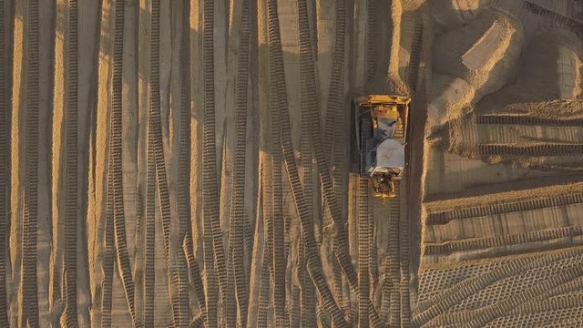 Construction site on the road construction site. Bulldozer dubs sand and soil on a summer evening at sunset. Aerial view