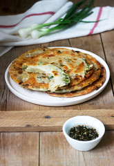 Homemade appetizing scallion pancakes and a bunch of green onions. Rustic style.