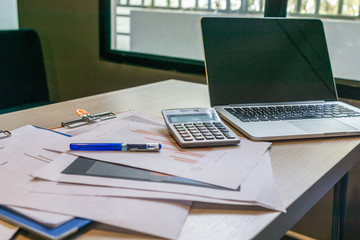 Naklejka na ściany i meble Unorganized messy desk with laptop , calculator and documents at workplace