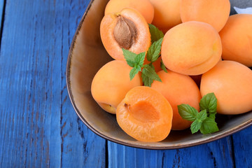 Ripe apricots in a ceramic bowl on the blue table