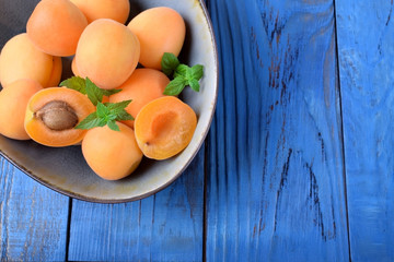 Ripe apricots in a ceramic bowl on the blue table
