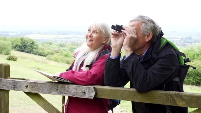 Retired Couple On Walking Holiday Looking Through Binoculars                          