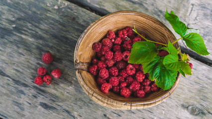 organic fresh raspberries in a wooden bowl on old wooden table background. Rustic style.