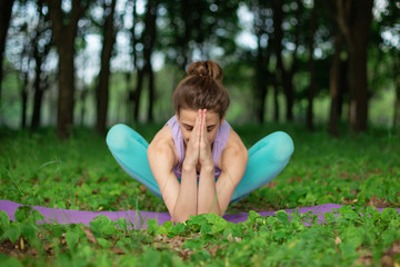 Thin brunette girl plays sports and performs beautiful and sophisticated yoga poses in a summer...