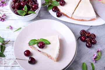 Piece of pie with sour cream and cherries topped with mint on the white plate