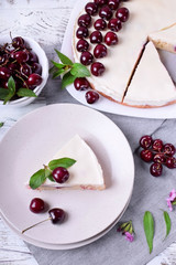 Piece of pie with sour cream and cherries topped with mint on the white plate