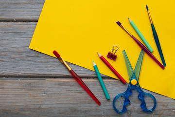 Childrens art and craft composition. Art supplies and yellow paper on a desk