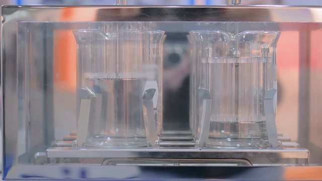 Pharma industry, medicine and science concept - pharmaceutical testing equipment - automatic tablet disintegration and dissolution apparatus with two basket at pharmacy factory or exhibition