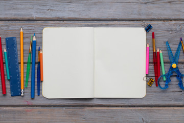 Blank notepad and childrens art supplies on a wooden background