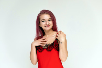 Concept portrait of a pretty sexy girl with purple hair in beautiful red lingerie on a white background. She smiles, happy with life, happy. Hair flying, front view. Made in a studio.