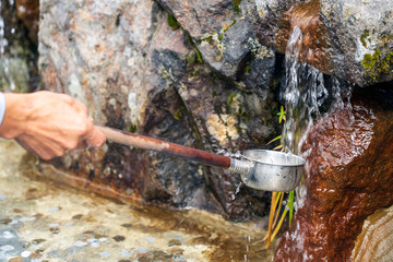 Hand Is Filling The Dipper Or The Ladle By Drinkable Water.