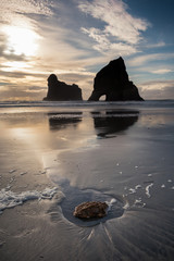 Atardecer en la playa, formaciones de rocas en el mar y el reflejo de la arena