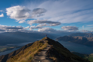 Hombre mirando el paisaje entre el cielo y el lago luego de un largo camino