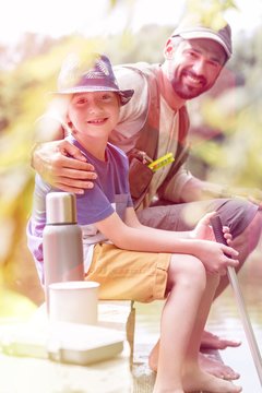 Portrait of smiling father and son sitting on pier