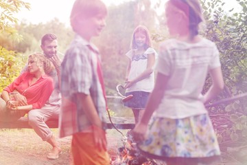 Naklejka premium Kids standing at campsite while parents sitting on bench in public park