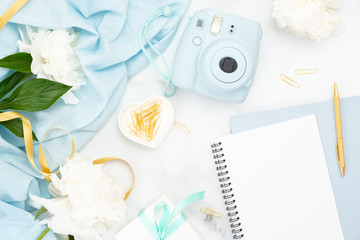 Flatlay of feminine home office desk. table. Fashion blogger workspace with pastel blue instant camera, peony flowers and decorations on marble background. Flat lay, top view beauty blog banner mockup