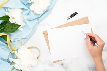 Top view woman hand writing wedding invitation card or love letter. Minimal flat lay composition...