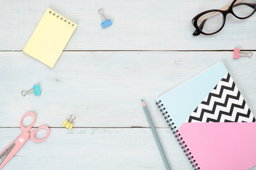 Top view teenage girl home office desk. Flat lay beauty blogger workspace with paper notepad, stationery and feminine accessories on pastel blue wooden background. Fashion blog hero banner mockup