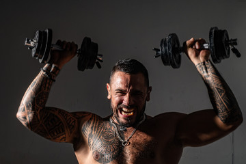 Young Muscular Bodybuilder Guy Doing Exercises With Dumbbells Over Dark Background. Intense workout.
