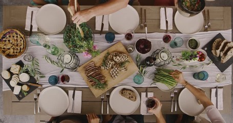 Friends having a dinner party together, top down view of dinner table with six friends serving food and making dinner plates - Powered by Adobe
