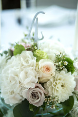 Wedding table setting is decorated with fresh flowers and white candles. Wedding floristry. Bouquet with roses, hydrangea and eustoma. Table numbering