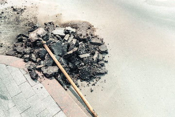 The shovel next to the pieces of the old asphalt pavement, repair works of the road. Place for text