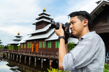 Good looking Asian photographer man taking photo at the Nepal pagoda tourist attraction.