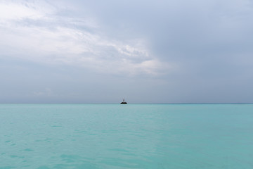 The guy is standing on a rock in the middle of the ocean and waving his arms. A person needs help