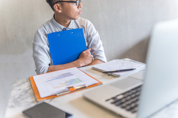 Office man sitting at work place holding folder and thinking 
