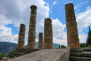 Entrance to ancient greek temple of apollo in Delphi, Greece under blue sky with clouds