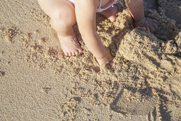 Little toddler girl playing with sand at the beach	