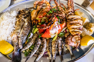 mixed grilled fish with Greek salad, rice and lemon for dinner
