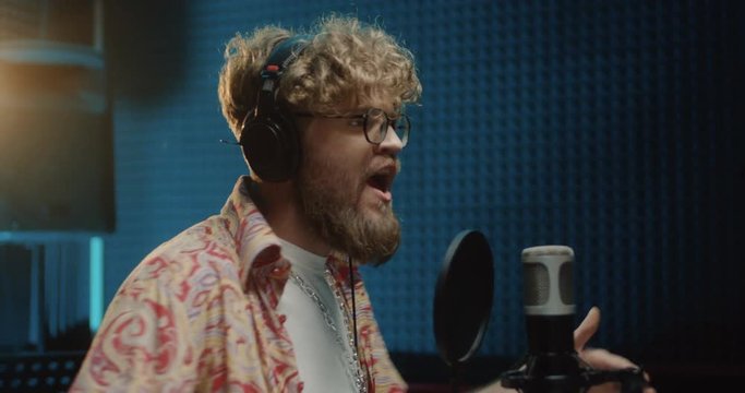 Process pf the recording of the song and vocal part by the male young Caucasian singer while he singing emotionally in the microphone.
