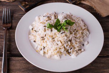 Basmati rice with herbs on a white plate on a wooden table