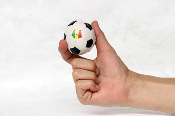 Fototapeta premium Mini ball of football in hand and one black point of football is Senegal flag, hold it with two finger on white background.
