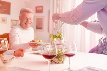 Woman serving salad to smiling man at dining table