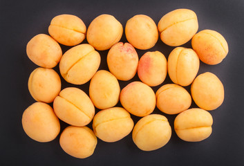 Apricots on black background. top view.