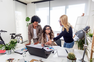 Group of three multhietnic serious woman in front of laptop at the office